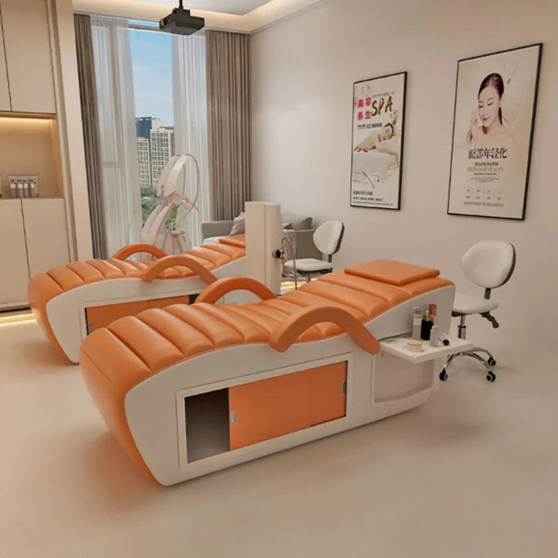 Two modern orange and white professional massage beds with built-in side storage in a bright spa room.