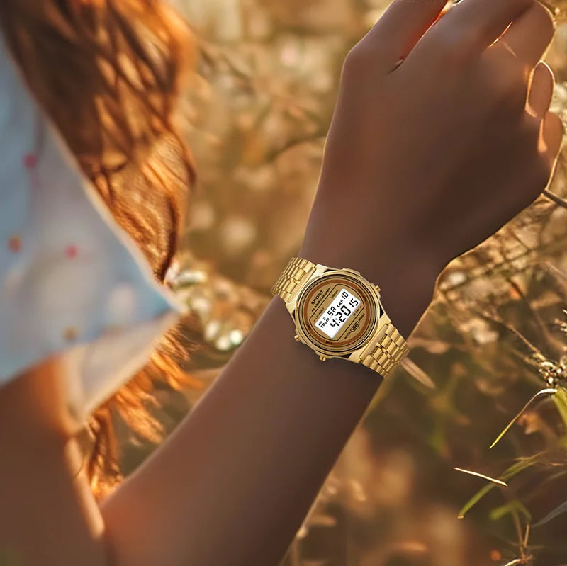 A gold-toned retro-style digital watch with a matching link bracelet worn on a woman's wrist.