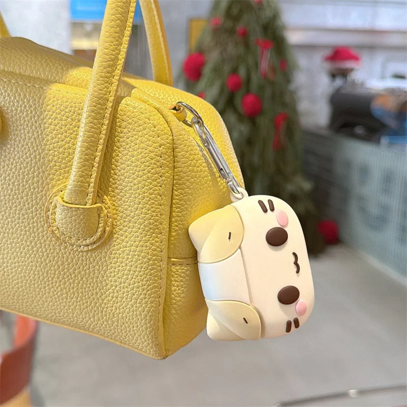 Cute cream silicone AirPods Pro case with cat face design, attached to a yellow handbag with a silver keyring.