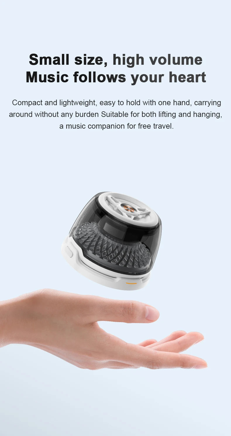 A hand holds a compact, white and black portable Bluetooth speaker with a transparent dome design.