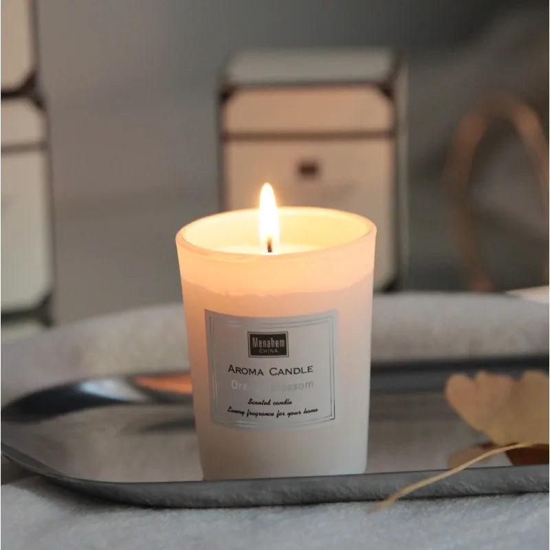 Lit orange blossom scented candle in a frosted white glass jar, presented on a silver tray.