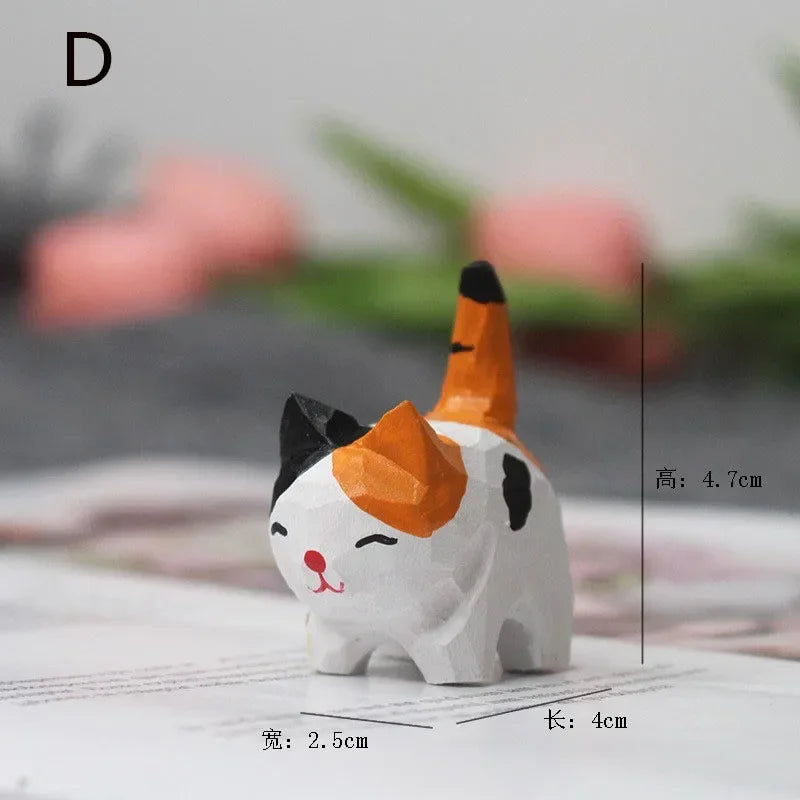 Small hand-carved wooden calico cat figurine with a painted white, black, and orange design and a happy expression.