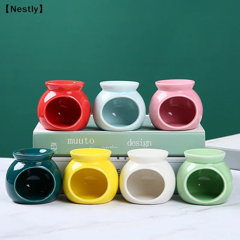 Set of seven colourful, round ceramic oil burners for wax melts in red, blue, pink, dark green, yellow, white, and mint.