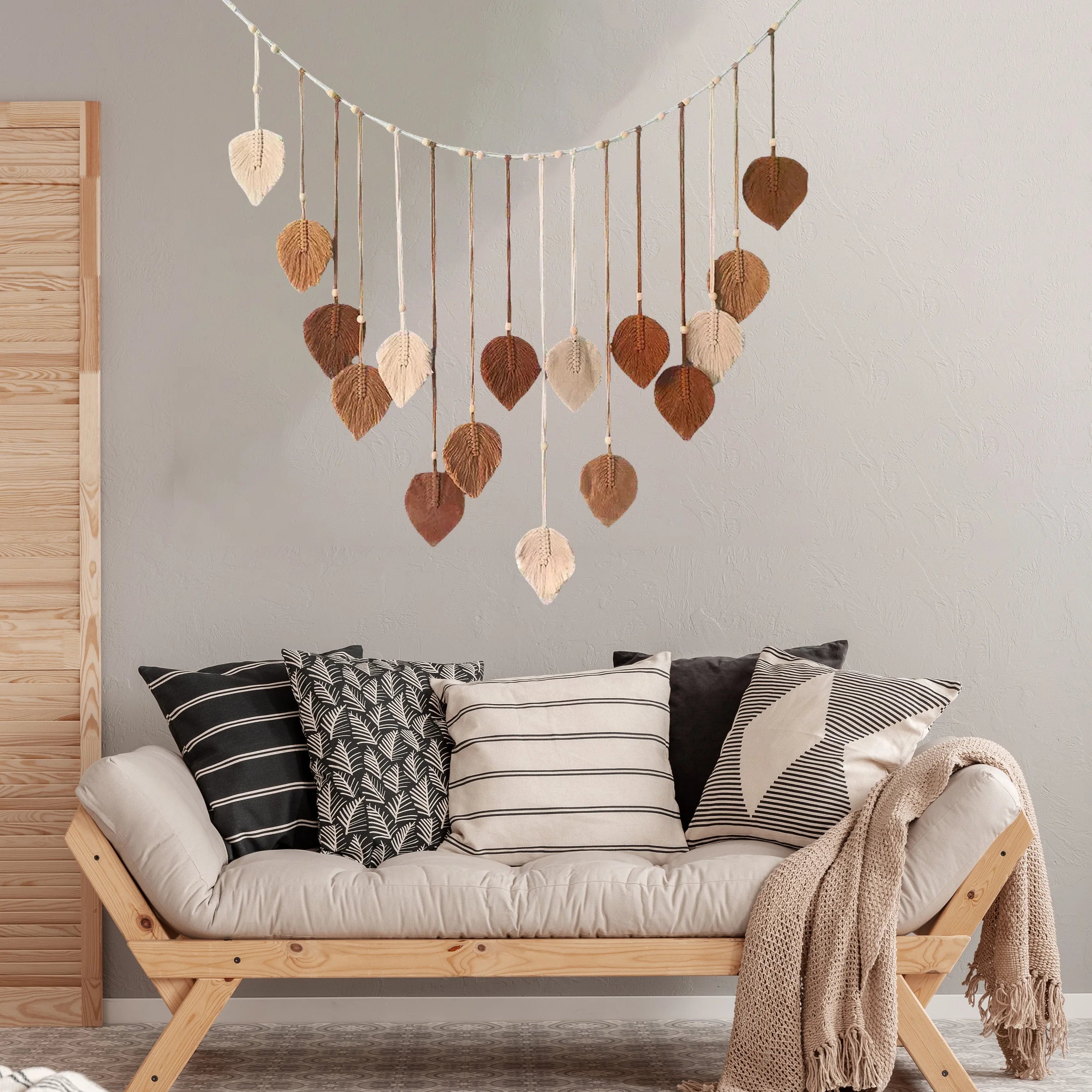 Boho macrame wall hanging with cascading leaf and feather tassels in varying shades of cream, beige, and brown.
