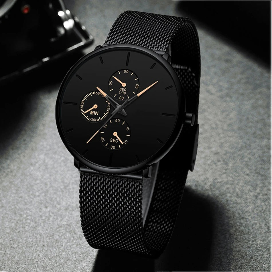 Ultra-thin men's watch in matte black with a stainless steel mesh strap, black dial, and gold-toned sub-dial hands.