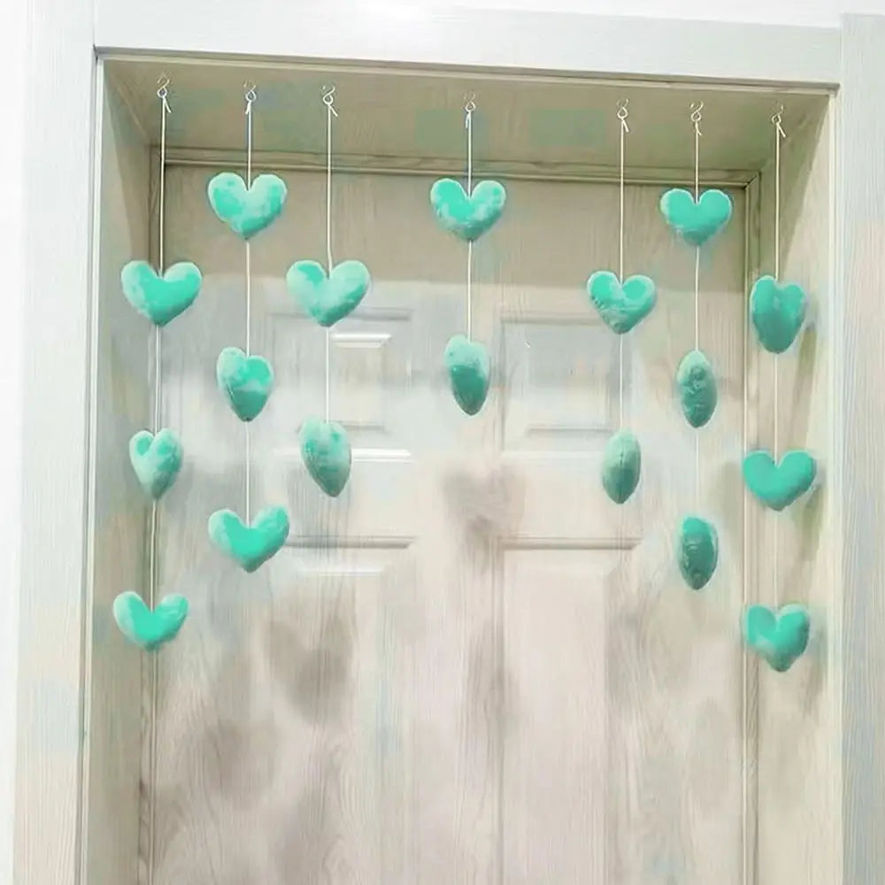 Rows of soft, mint-green fabric hearts hanging on strings, creating a decorative curtain in a door frame.