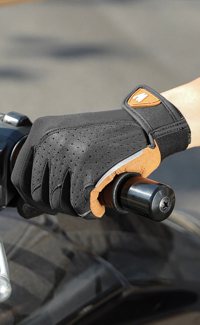 Black perforated motorcycle glove with tan suede trim and velcro strap, worn while gripping a motorcycle handlebar.