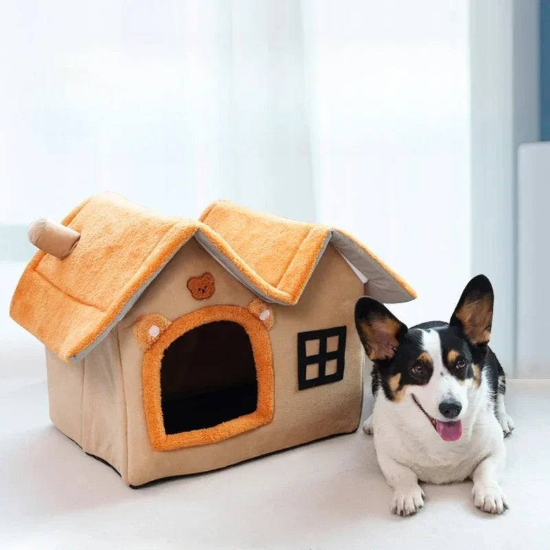 Beige and orange plush dog house cave bed with bear details, chimney, window, and a Corgi sitting beside it.