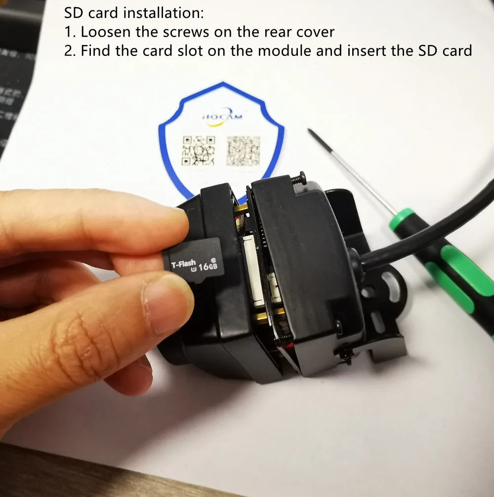A person inserts a 16GB black plastic SD card into a black plastic camera module using a small screwdriver.
