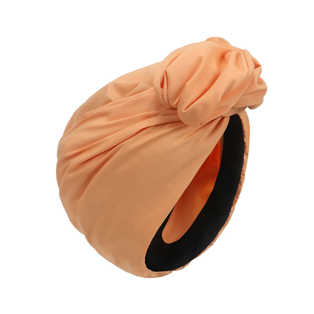 Peach-coloured vintage-style turban hat with a knotted front detail and a black interior lining.
