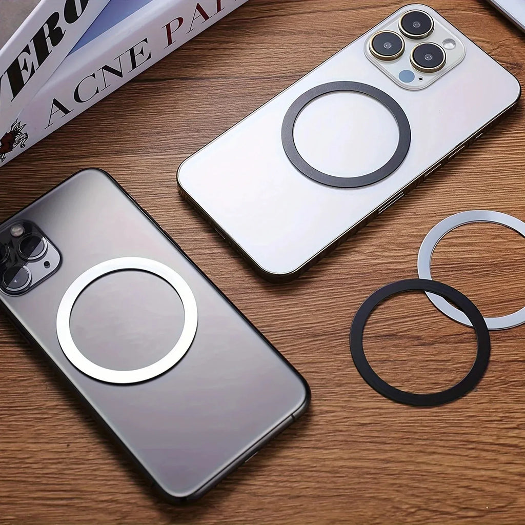 Two smartphones on a wooden desk with circular magnetic rings attached to the back, plus extra black and silver rings.