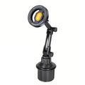 Black car cup holder phone mount with an adjustable arm and a circular magnetic head featuring an orange center accent.