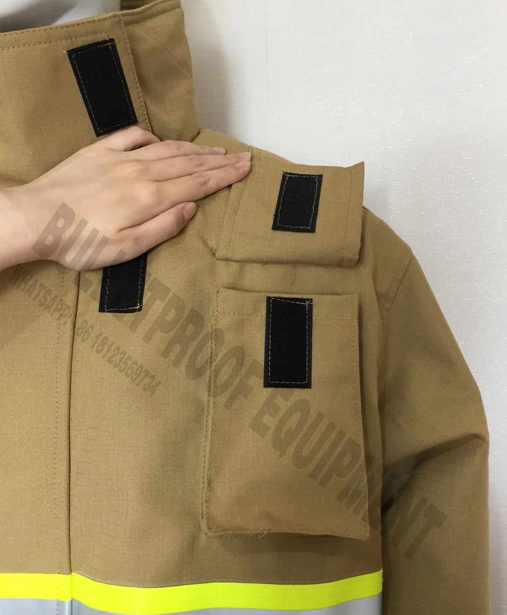 Tan tactical jacket with high collar, velcro closures, chest pockets, and high-visibility yellow strip at the base.