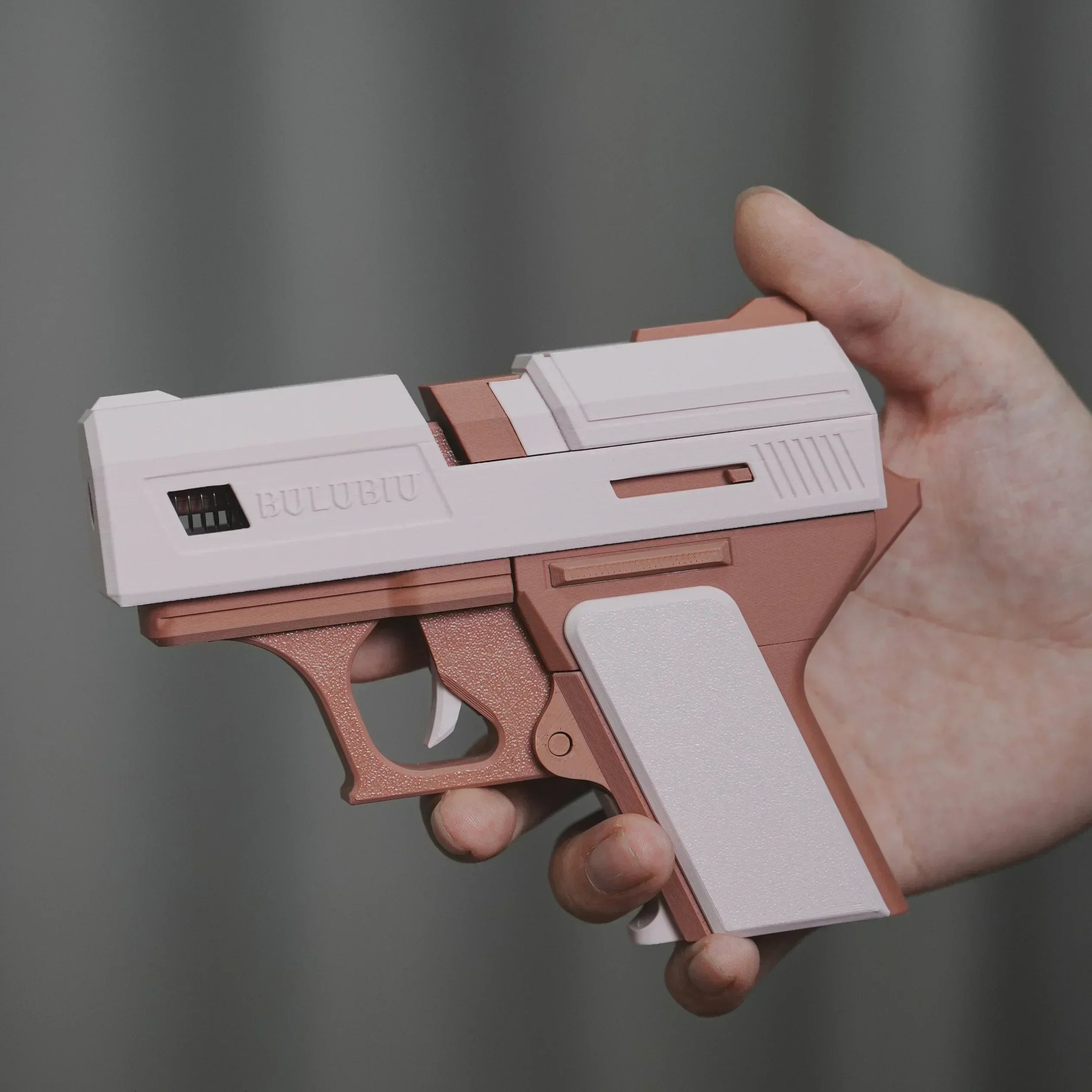 White and rose gold toy gun-style AirPod case in matte plastic, held in a hand. Suitable for standard AirPods.