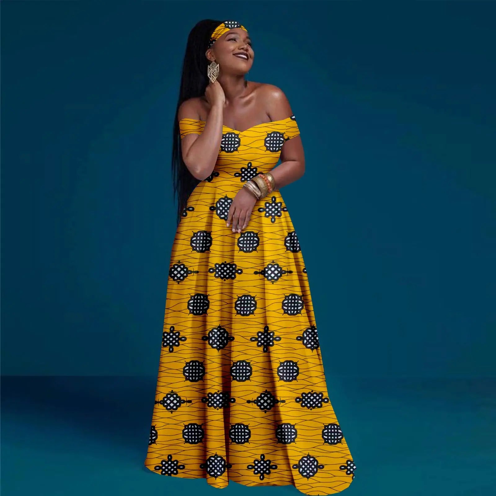 Model wearing a yellow off-shoulder maxi dress with a black and white geometric pattern and matching headband.