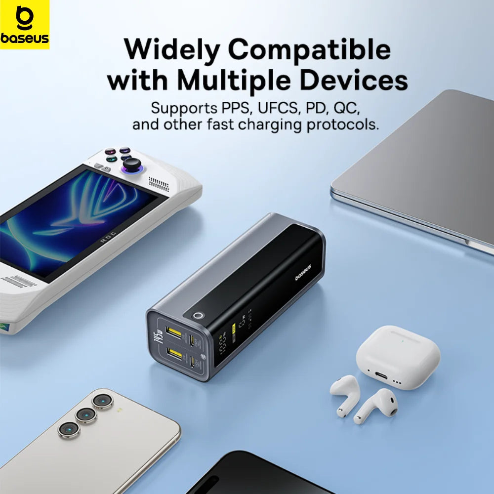 Grey, rectangular 145W fast-charging power bank with digital display, surrounded by a gaming console, phone, and earbuds.