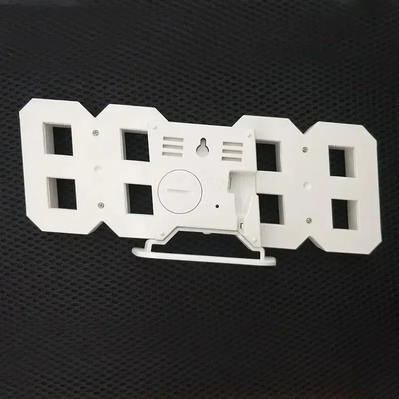 White, modern 3D digital LED clock. Rear view showing its built-in stand, wall-mount slot and battery compartment.
