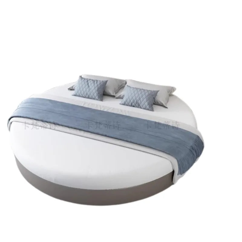 Modern circular bed frame in grey with white bedding, blue runner and matching quilted cushions.