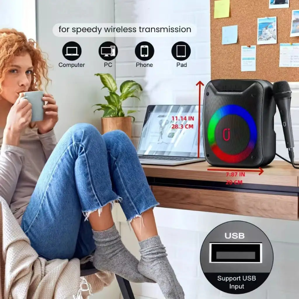 Compact black portable speaker featuring a vibrant LED light ring and an included microphone on a desk.