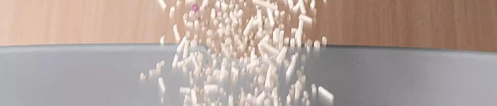 Grey waterproof cat litter mat with a smooth surface, shown as scattered litter beads are being poured onto it.