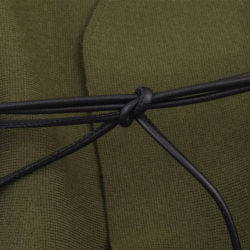 Close-up of an olive green knitted garment cinched with a thin, knotted black faux-leather cord belt.