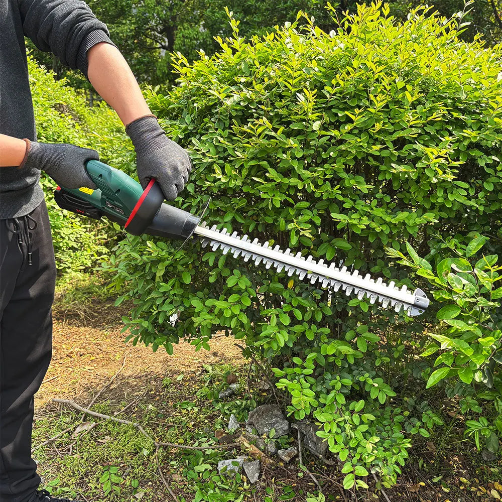 Green POSENPRO 20V cordless hedge trimmer with long metal cutting blade trimming a green bush.
