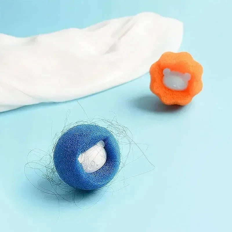 Orange and blue laundry lint remover balls with cute bear centres, one collecting hair, on a light blue background.