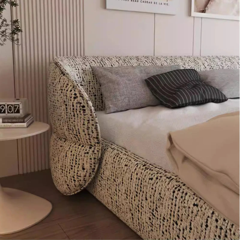 Modern bed frame in a textured cream and black flecked fabric with rounded, padded edges and a contemporary design.