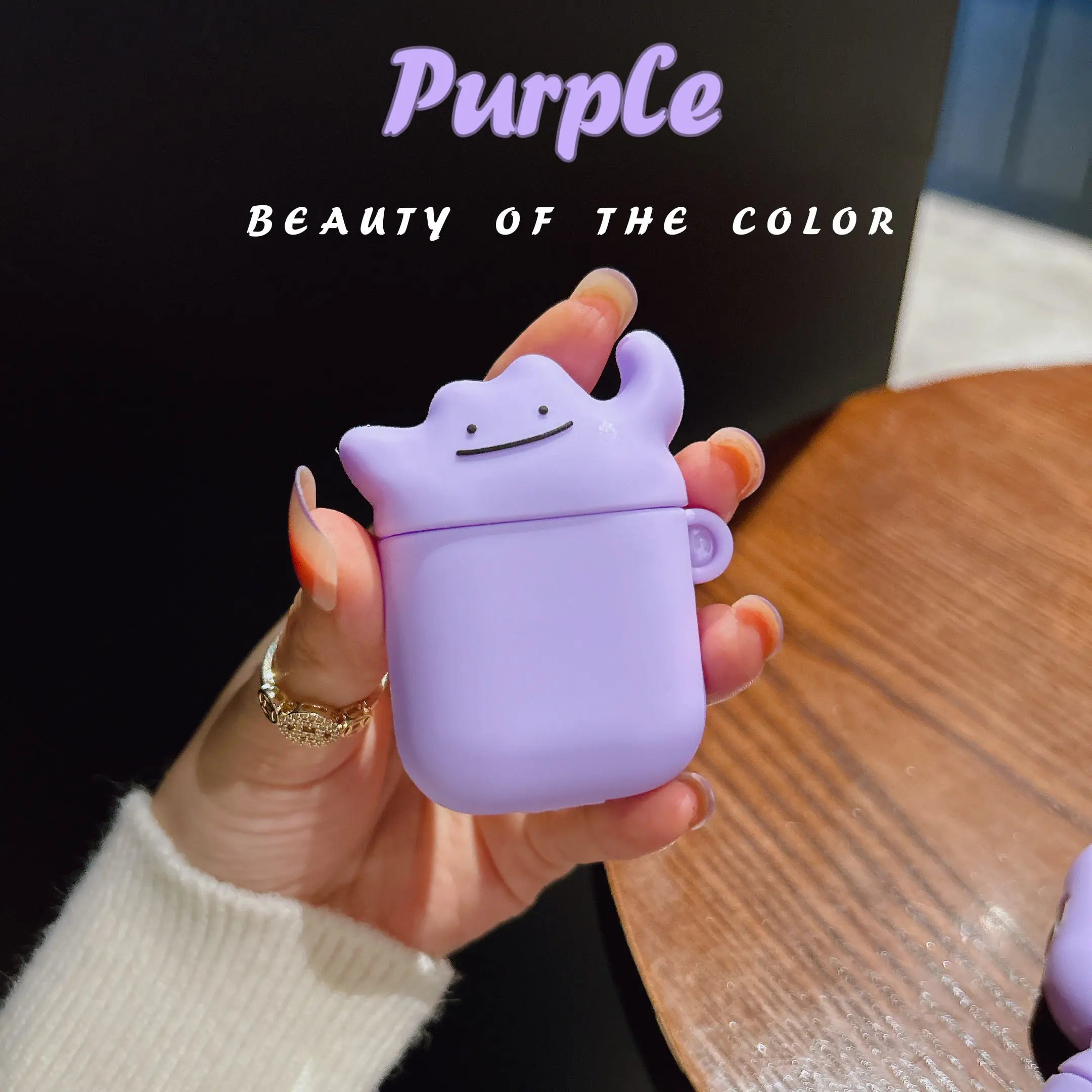 Purple silicone Ditto-style character AirPod case held in hand, compatible with standard AirPods.