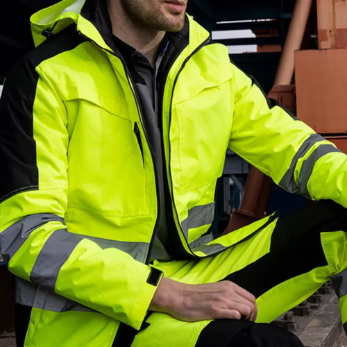 Model wearing a neon yellow and black 3-in-1 hi-vis waterproof jacket and trousers set with reflective tape strips.