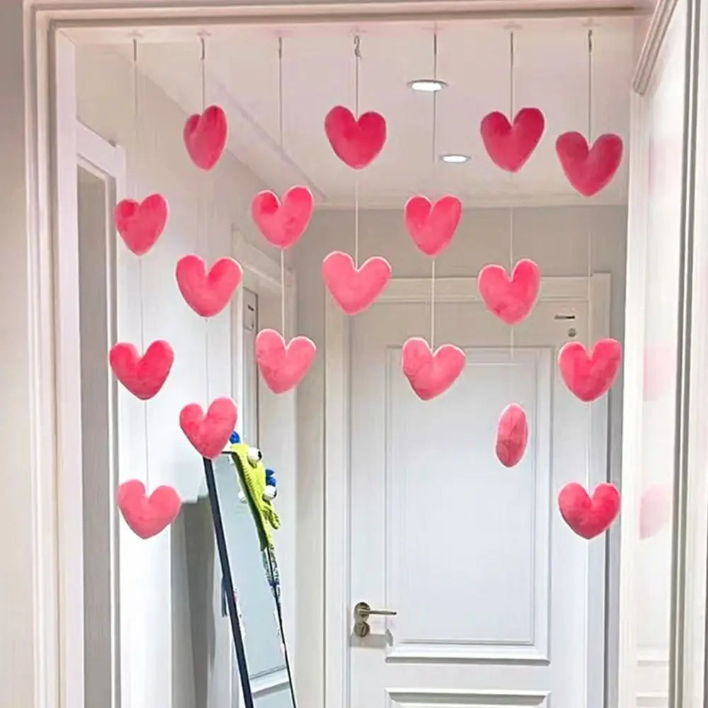 Hanging curtain decoration featuring rows of plush, soft-pink heart ornaments suspended from white strings in a doorway.