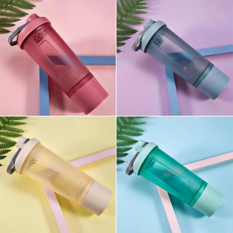 Four translucent, modern shaker bottles in pink, grey, yellow, and green, each with a carrying loop and bottom cap.