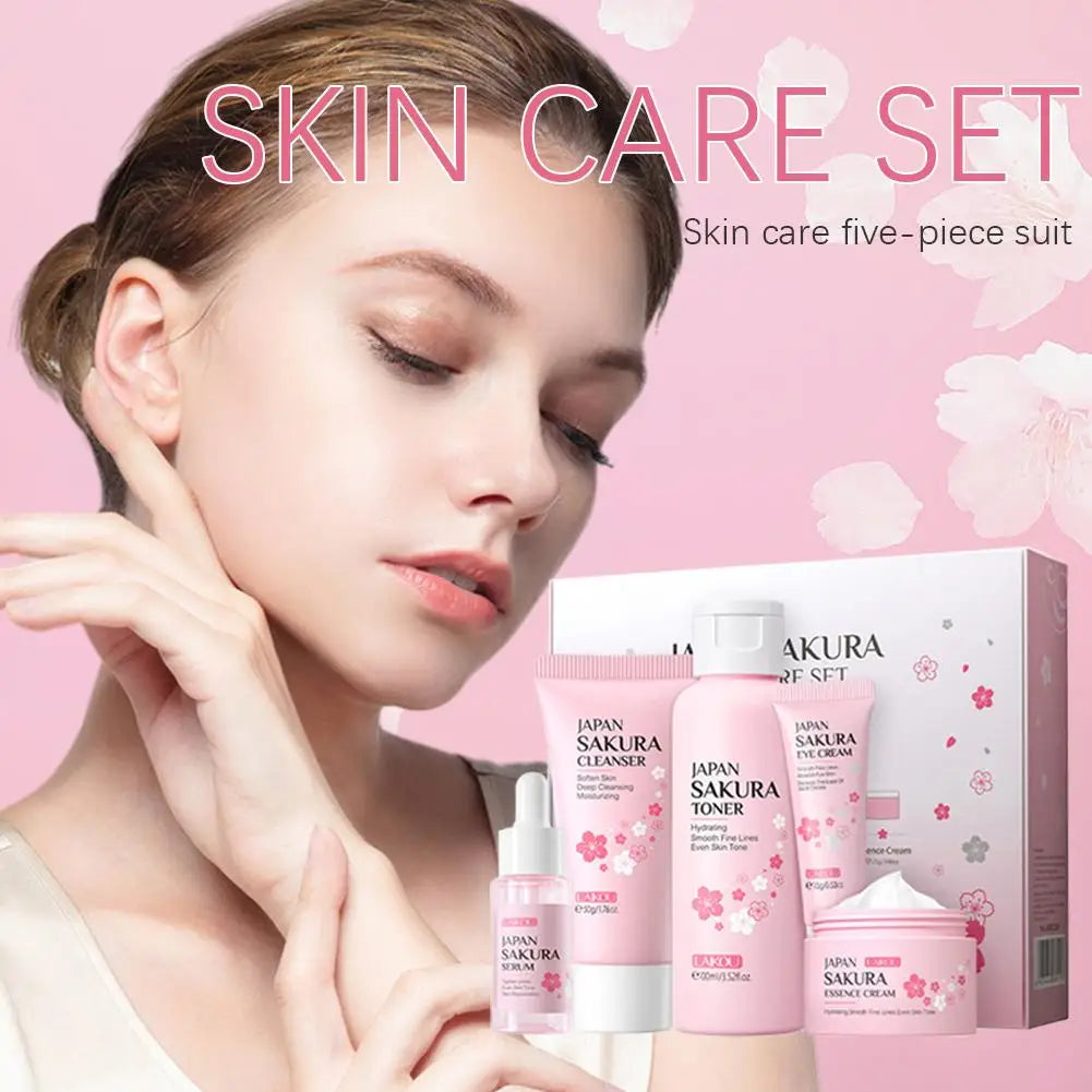 Five-piece pink sakura-themed skincare set including cleanser, toner, serum, eye cream, and face cream in a gift box.