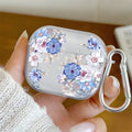 Clear AirPods case with blue and white floral print, includes silver carabiner. Suitable for AirPods Pro.