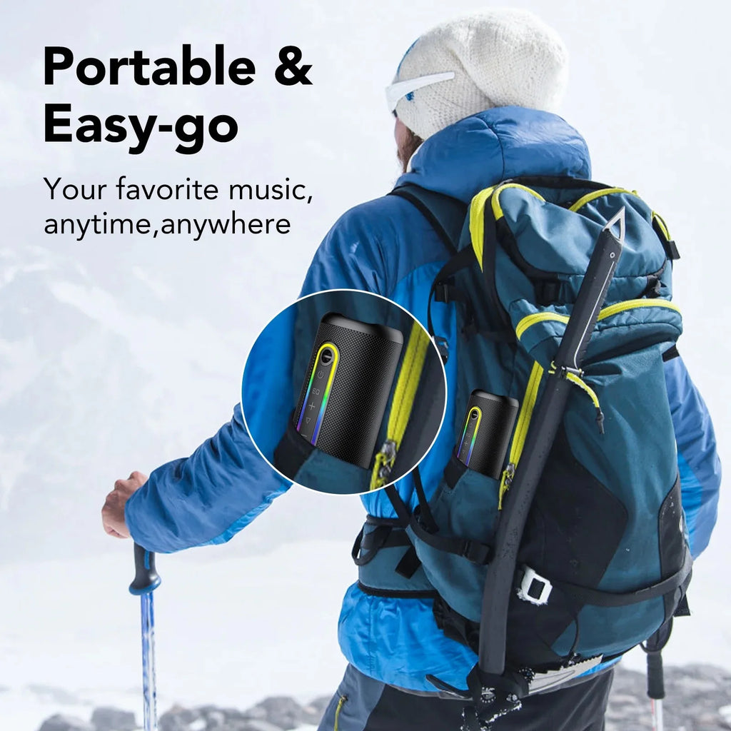Black portable Bluetooth speaker with vibrant LED light strip, attached to a hiker’s backpack in a snowy mountain scene.