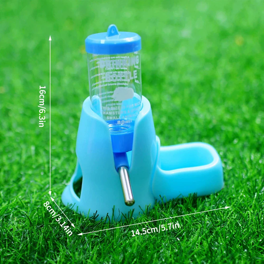 Blue small animal water bottle with integrated food bowl, standing on green grass, featuring measurement overlays.