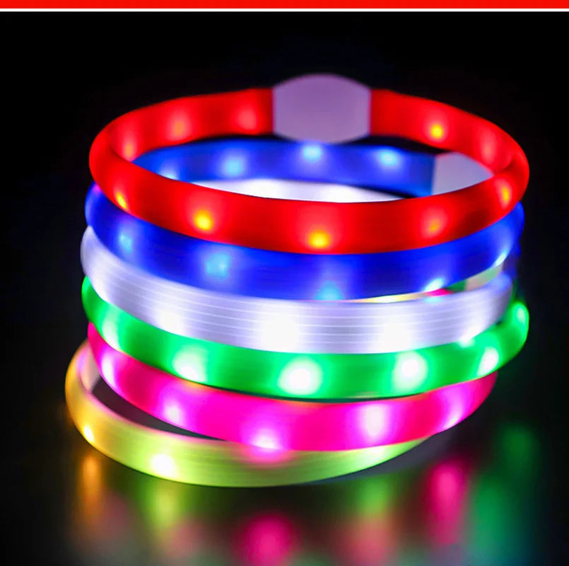 A stack of colourful, glowing LED dog collars in red, blue, white, green, pink and yellow against a black background.