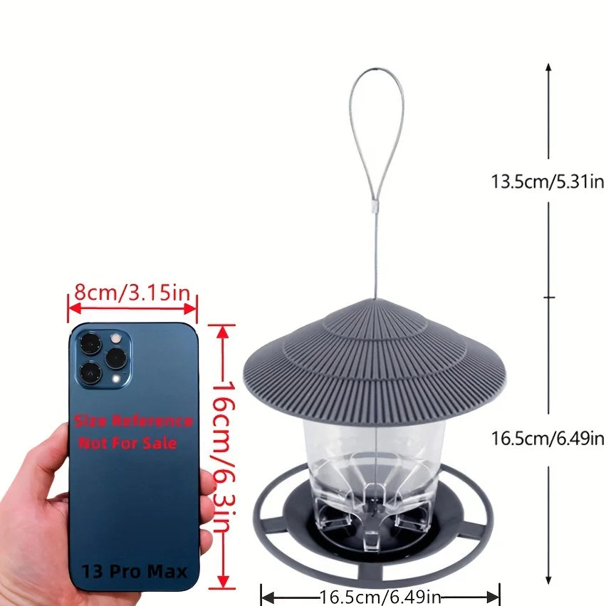 Grey hanging bird feeder with a pagoda-style roof, clear seed reservoir, and circular perch, shown with size markings.