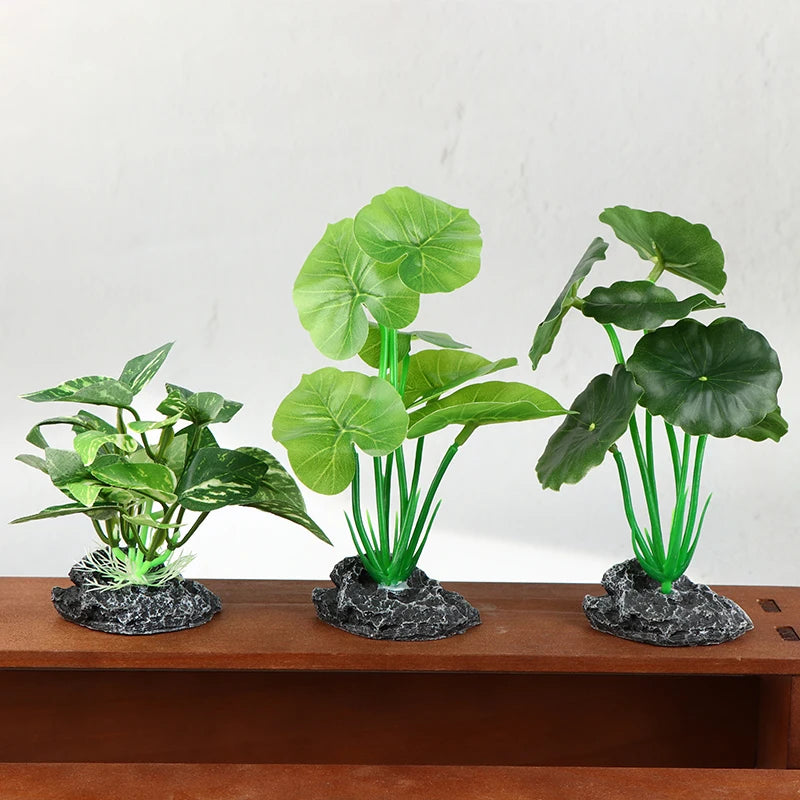 Three artificial aquarium plants with green leaves and stems, each anchored by a realistic gray stone-like base.