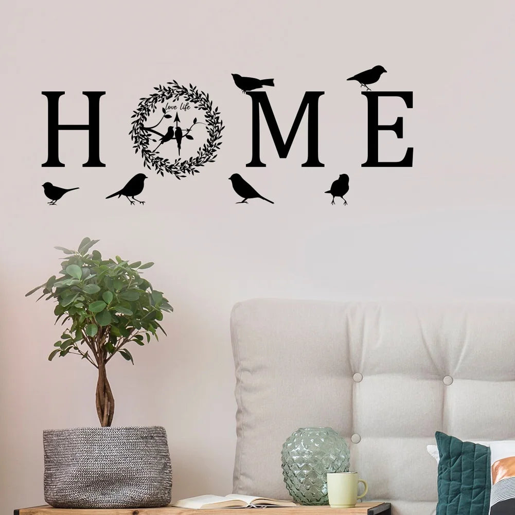 Black self-adhesive wall sticker featuring the word 'HOME' with a leaf wreath and bird silhouettes.