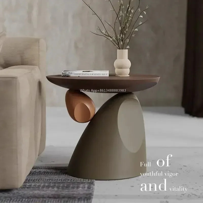 Minimalist side table in cream and brown with a unique sculptural, tiered base, set next to a neutral-toned sofa.