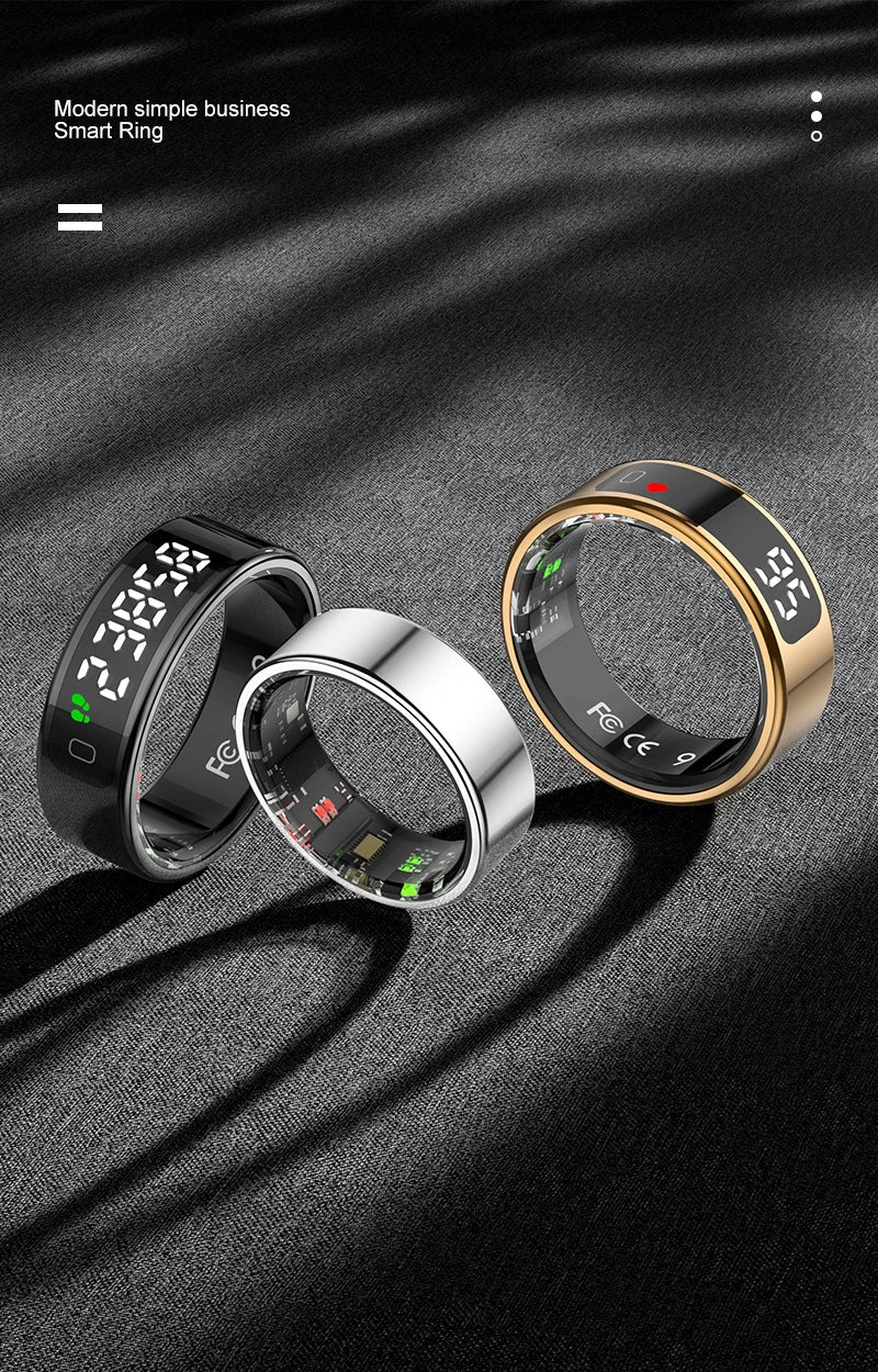 Three smart fitness rings in black, silver, and gold, each featuring a digital touch display on a dark textured surface.