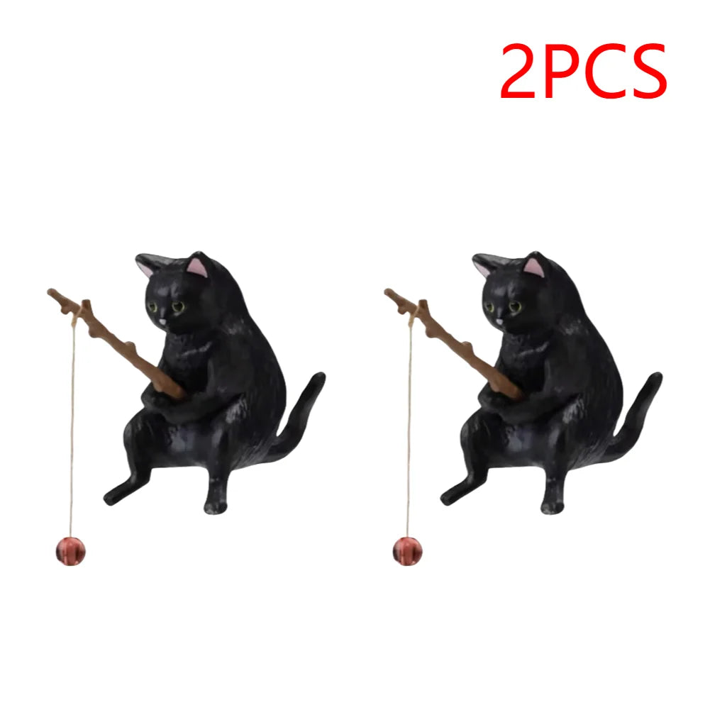 Set of two black cat aquarium ornaments, each holding a small twig fishing rod with a hanging bauble.