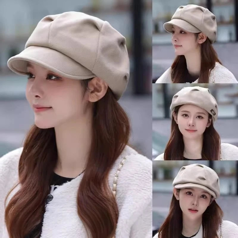 A woman wearing a beige retro-style newsboy beret with a structured peak and soft, pleated crown.