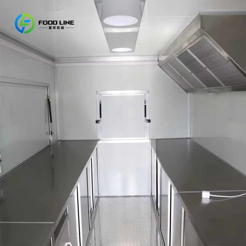White food trailer interior with stainless steel counters, range hood, and service windows.