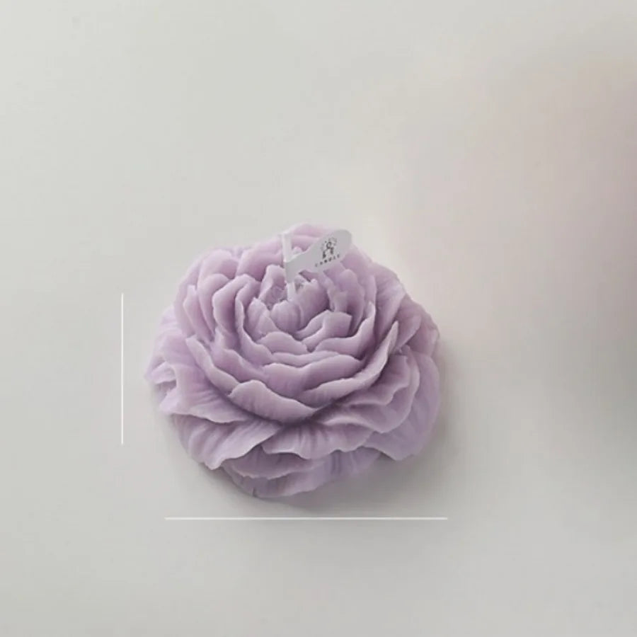 A pale lilac decorative candle shaped like a detailed, layered blooming rose flower on a white background.
