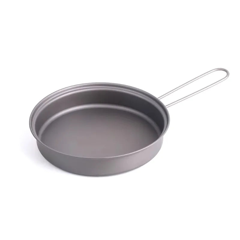Grey metal frying pan with a folded wire handle, isolated on white.