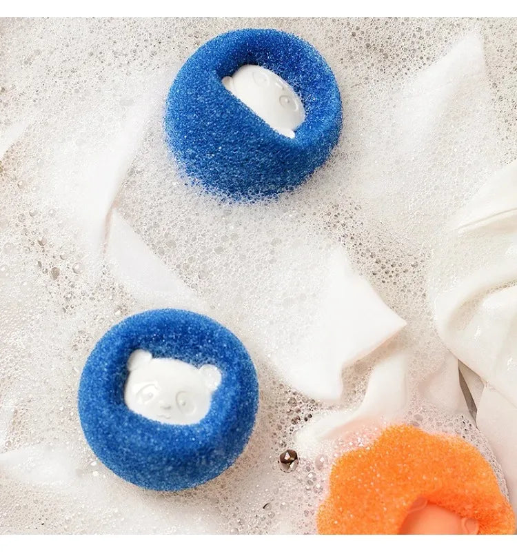 Two blue circular sponges with white panda-shaped centres resting in soapy water.