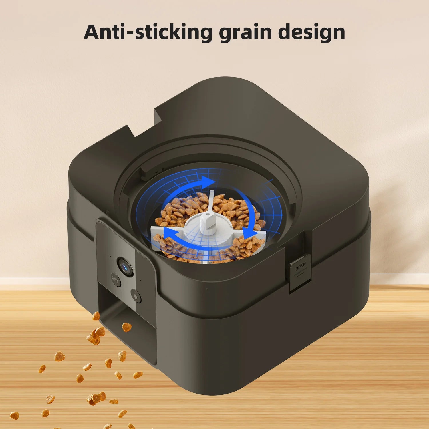 Black automated pet food dispenser with a non-stick rotating mechanism dispensing kibble on a wooden surface.