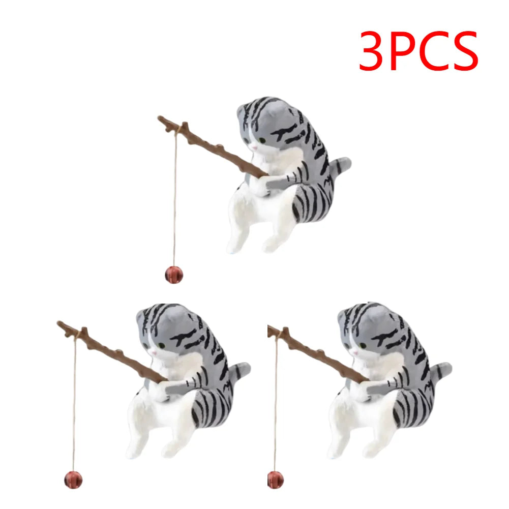 Three cute, grey-striped tabby cat ornaments, each holding a twig fishing rod with a small red bobber.